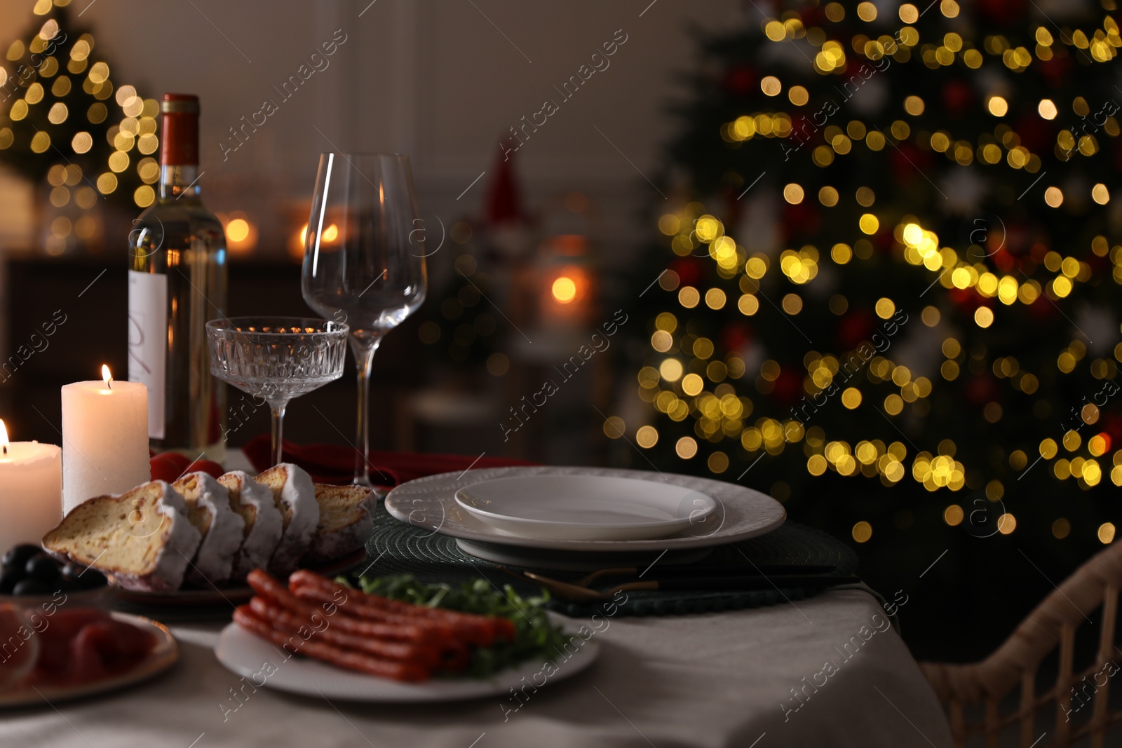 Photo of Christmas table setting with burning candles, appetizers and dishware indoors