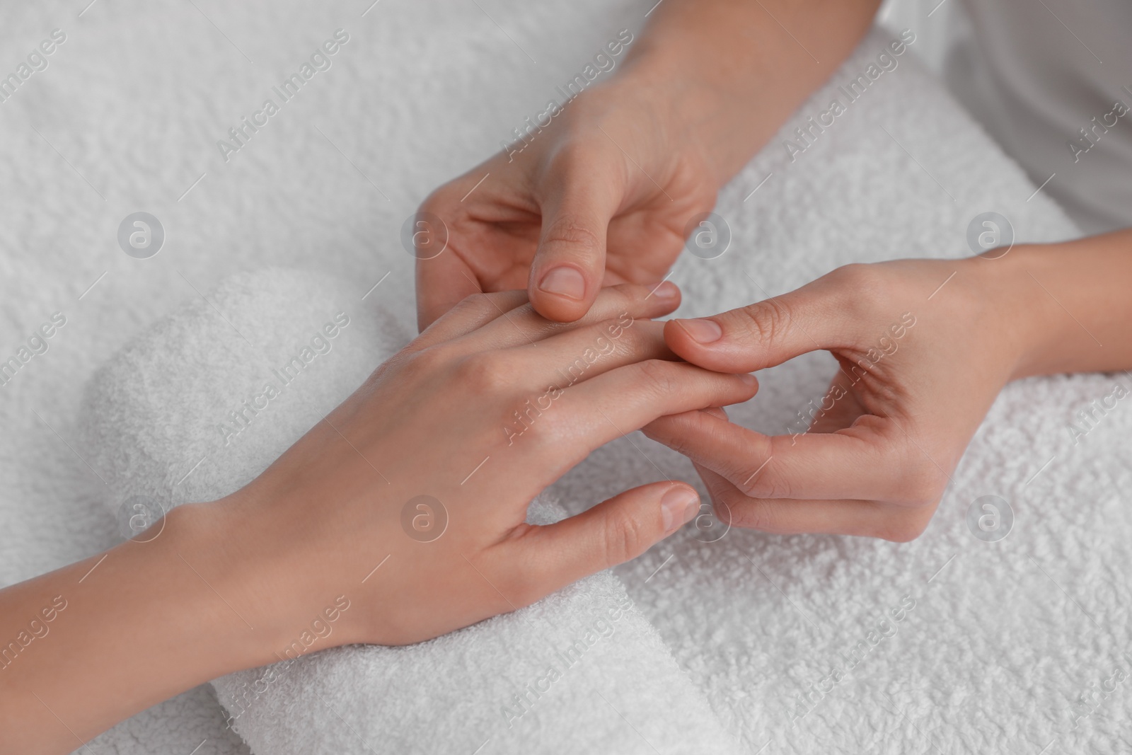 Photo of Woman receiving hand massage on soft towel, closeup