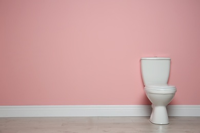 New ceramic toilet bowl near color wall with space for text