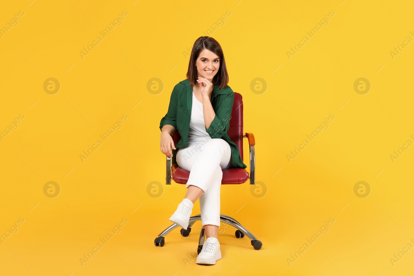 Photo of Young woman sitting in comfortable office chair on yellow background