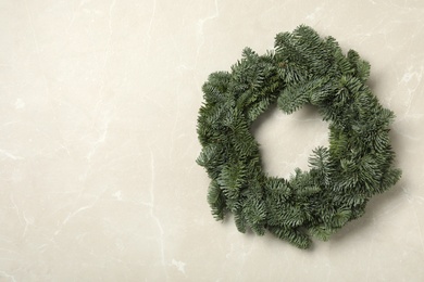 Photo of Christmas wreath made of fir tree branches on light grey marble background, space for text