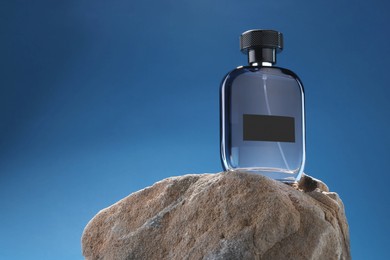 Photo of Stylish presentation of luxury men`s perfume on stone against light blue background. Space for text