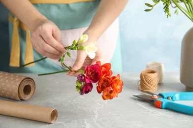 Woman making bouquet of freesia flowers at table, space for text