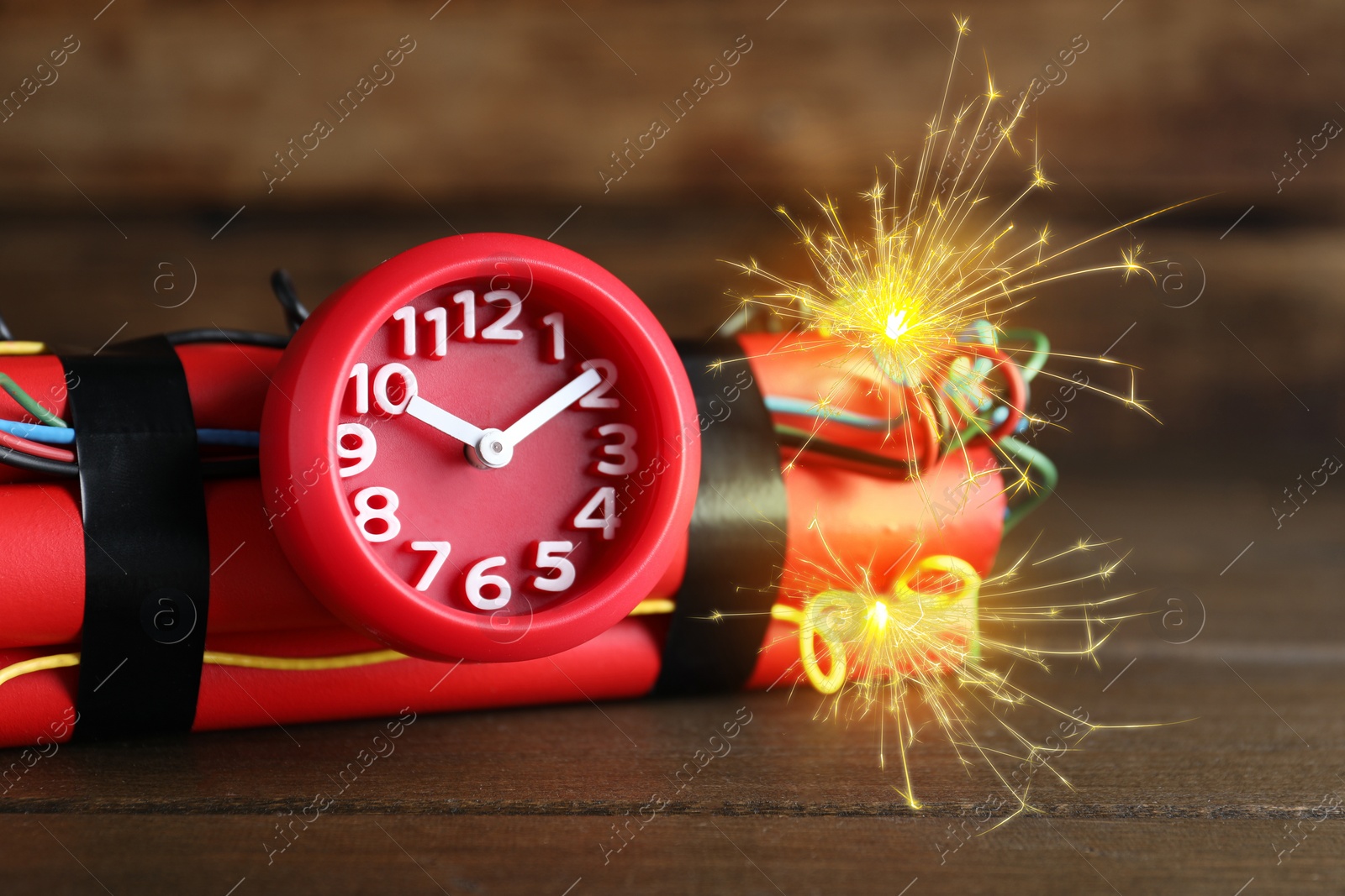 Image of Dynamite time bomb with burning wires on wooden table, closeup