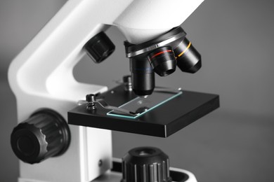 Modern medical microscope with glass slide on blurred background, closeup