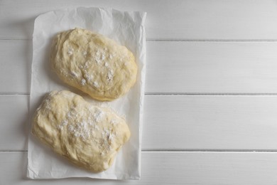 Photo of Raw dough and flour on white wooden table, top view with space for text. Cooking ciabatta