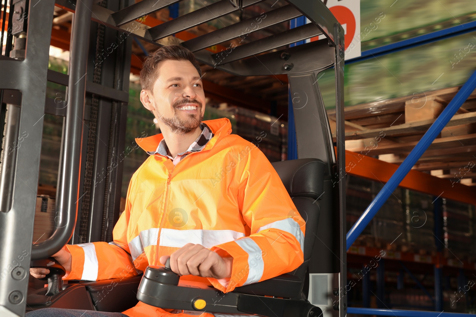 Photo of Happy worker sitting in forklift truck at warehouse