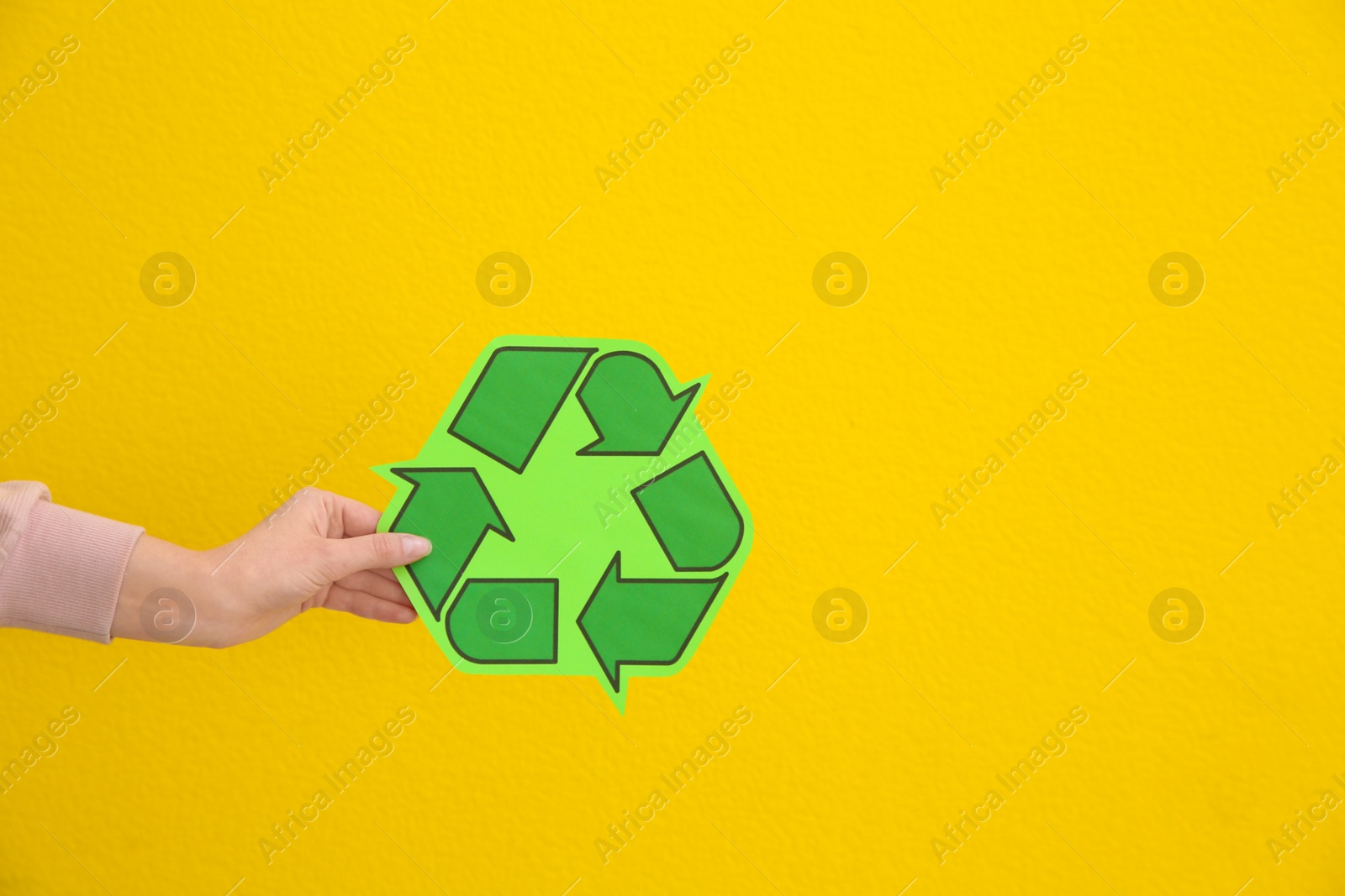 Photo of Woman holding recycling symbol on color background, closeup. Space for text