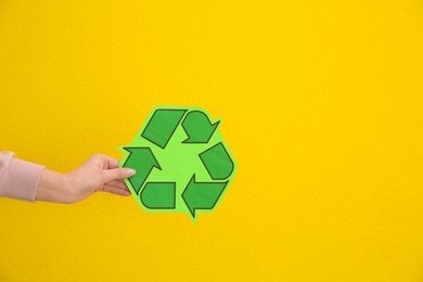 Woman holding recycling symbol on color background, closeup. Space for text