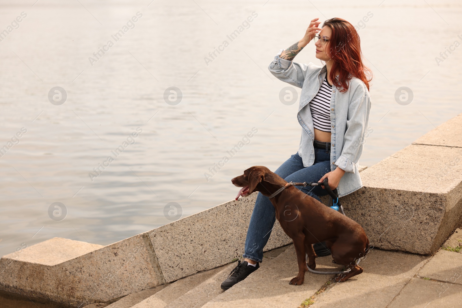 Photo of Woman with her cute German Shorthaired Pointer dog outdoors, space for text