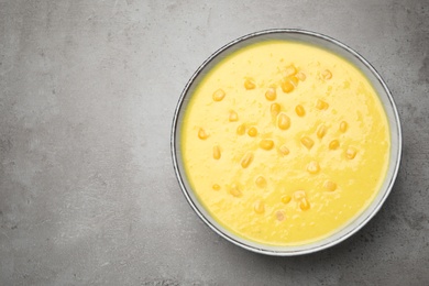 Delicious creamy corn soup on grey table, top view. Space for text