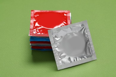 Condom packages on green background. Safe sex