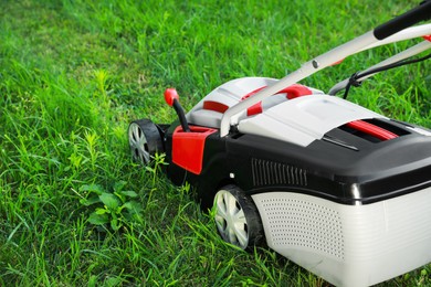 Photo of Cutting green grass with lawn mower in garden, space for text