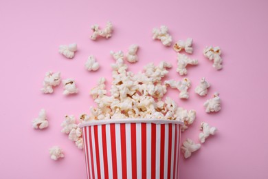 Photo of Bucket of tasty popcorn on pink background, flat lay