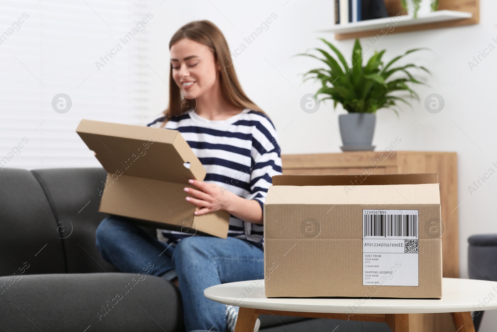 Photo of Happy woman unpacking parcel at home, selective focus. Online store