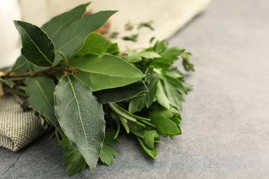 Photo of Aromatic bay leaves and different herbs on light gray table, closeup. Space for text