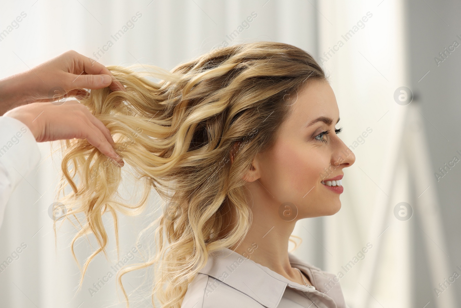 Photo of Hair styling. Professional hairdresser working with smiling client indoors, closeup