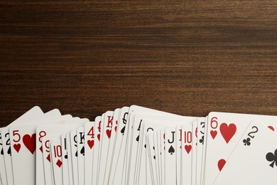 Photo of Deck of playing cards on wooden table, top view. Space for text