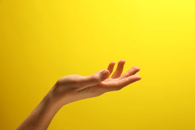 Photo of Woman holding something in hand on yellow background, closeup. Space for text