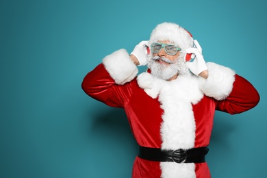 Photo of Santa Claus listening to Christmas music on color background