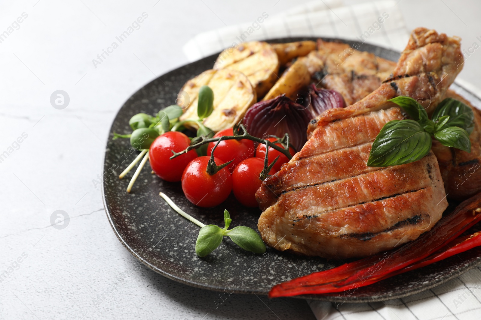 Photo of Delicious grilled meat and vegetables on light grey table, closeup