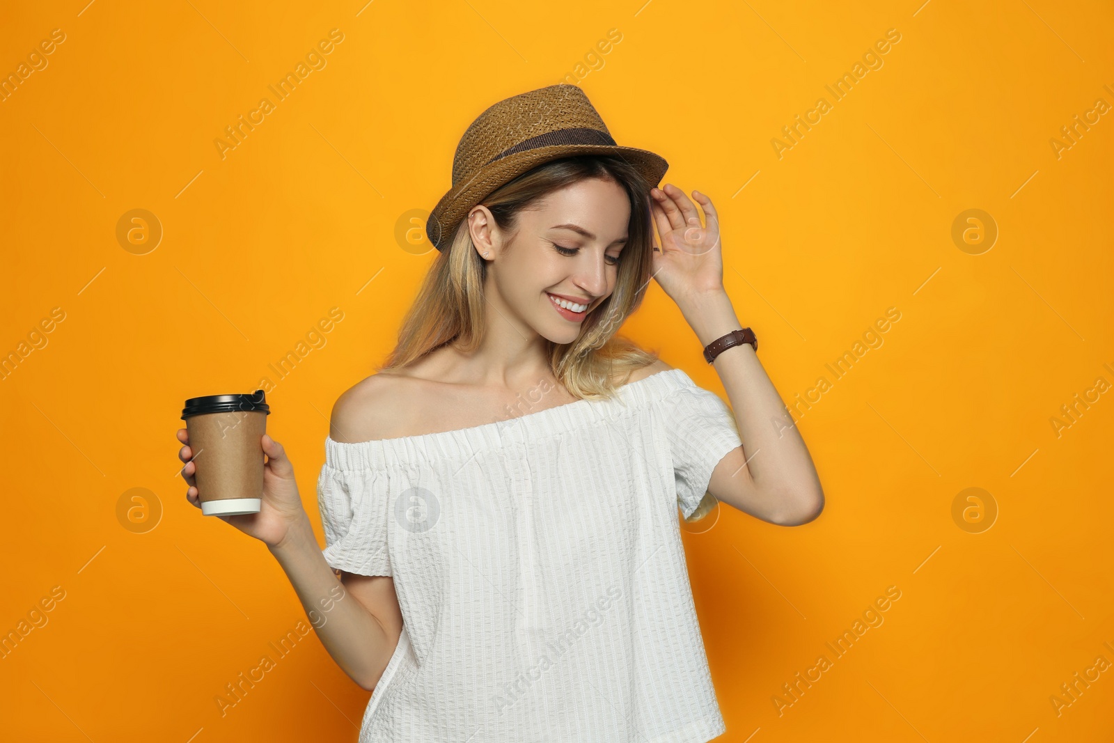 Image of Beautiful young woman with straw hat and coffee on orange background