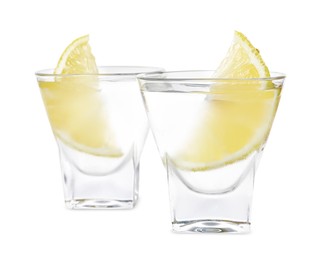 Photo of Shot glasses of vodka with lemon slices on white background
