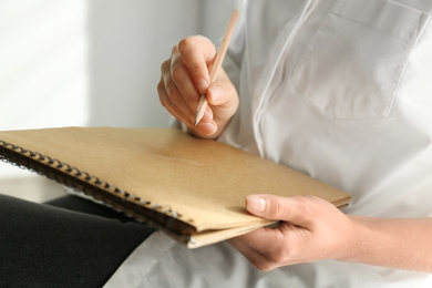 Photo of Woman drawing with pencil in notepad, closeup