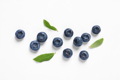 Tasty fresh blueberries with green leaves on white background, flat lay