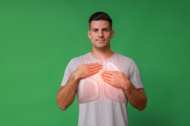 Handsome man holding hands near chest with illustration of lungs on green background