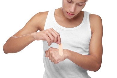 Handsome man putting sticking plaster onto hand on white background, closeup