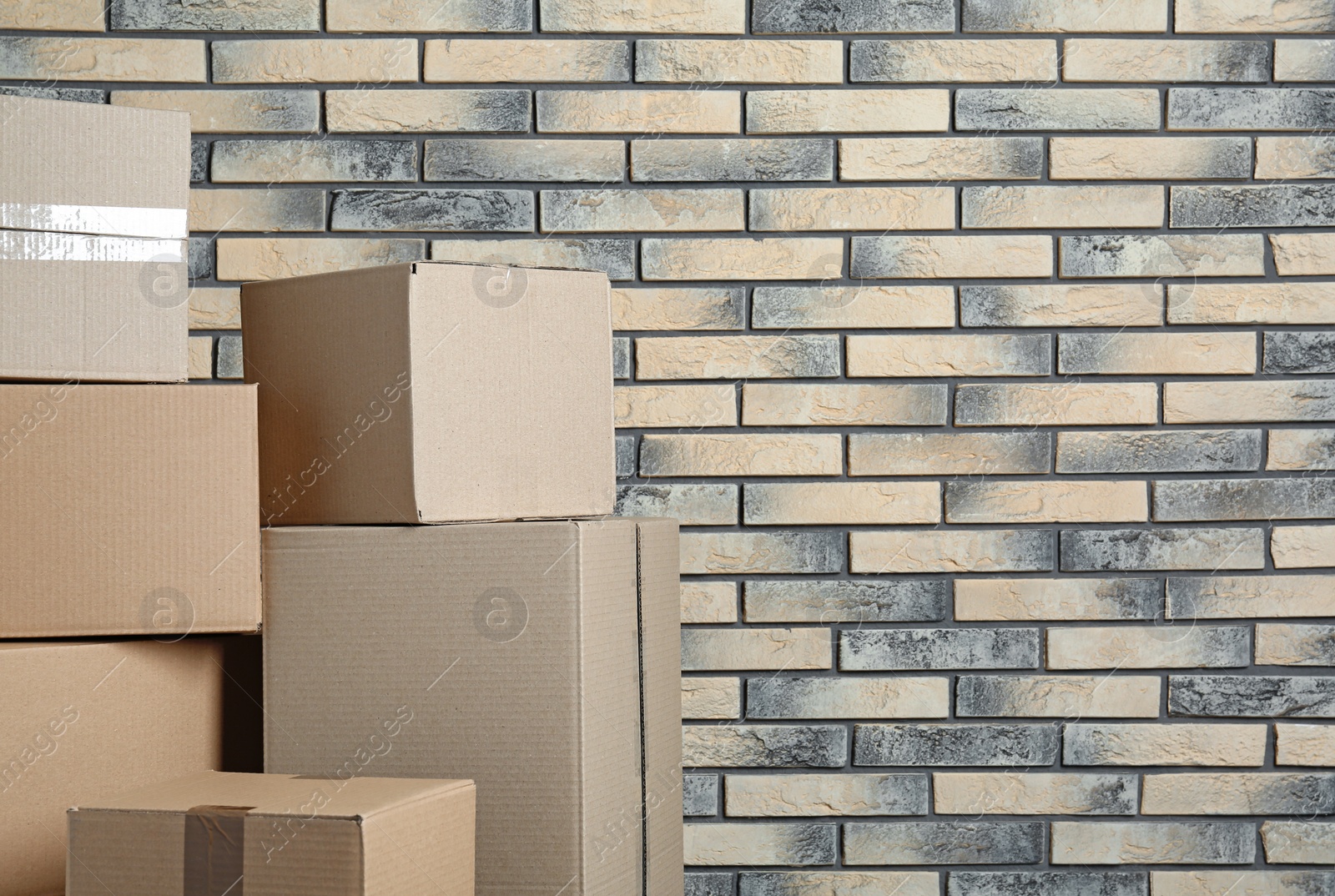 Photo of Pile of cardboard boxes near brick wall. Space for text