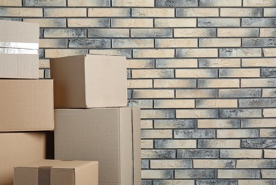 Photo of Pile of cardboard boxes near brick wall. Space for text