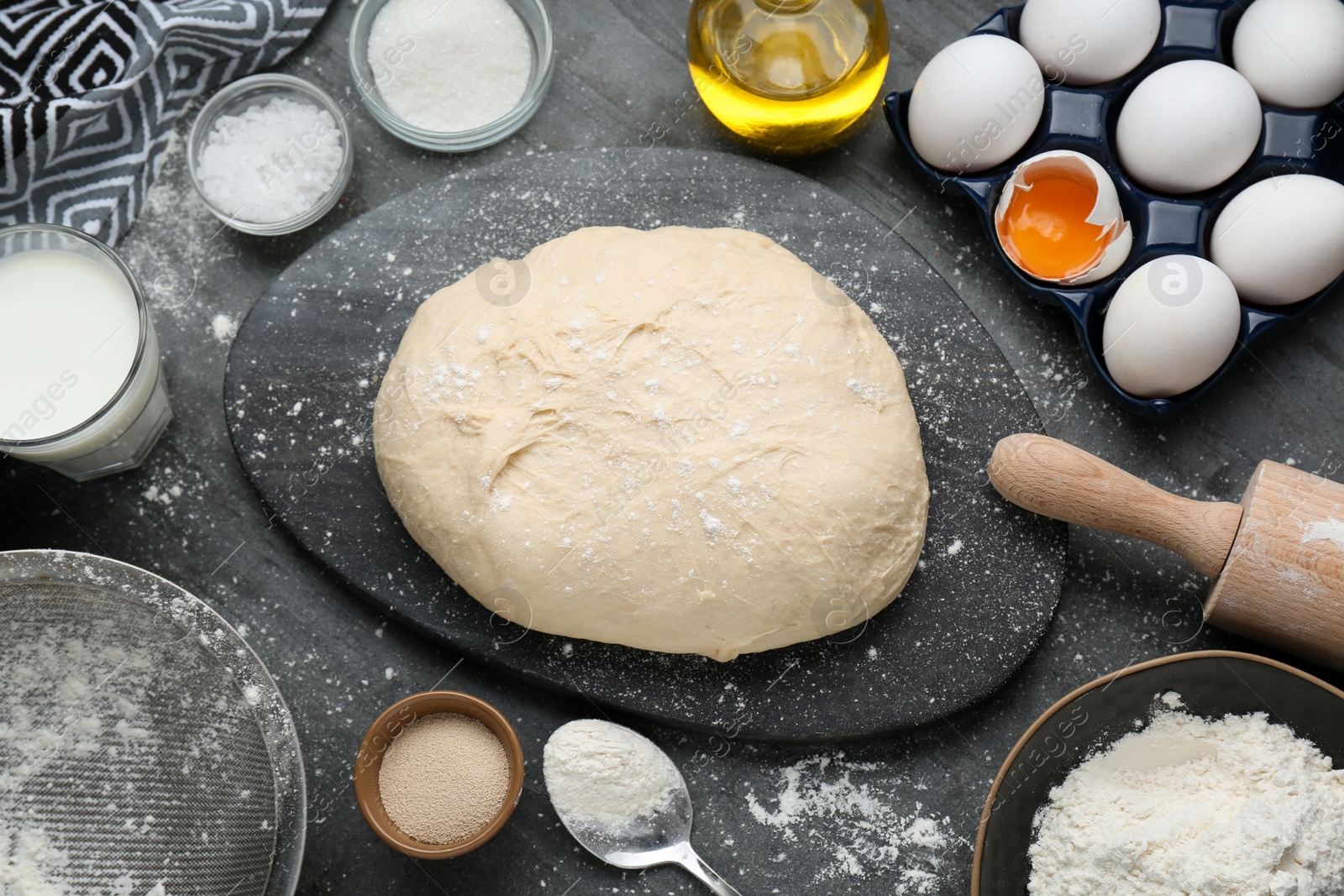 Photo of Fresh yeast dough and ingredients on black table, flat lay