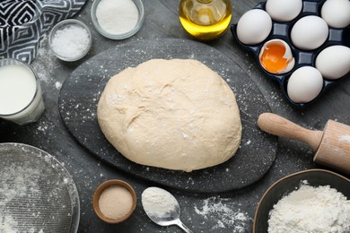 Fresh yeast dough and ingredients on black table, flat lay