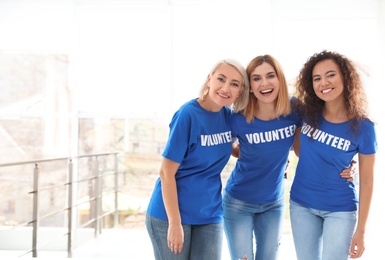 Portrait of happy female volunteers in uniform indoors. Space for text