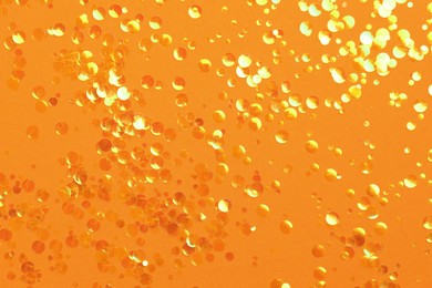 Photo of Shiny bright orange glitter on orange background, flat lay