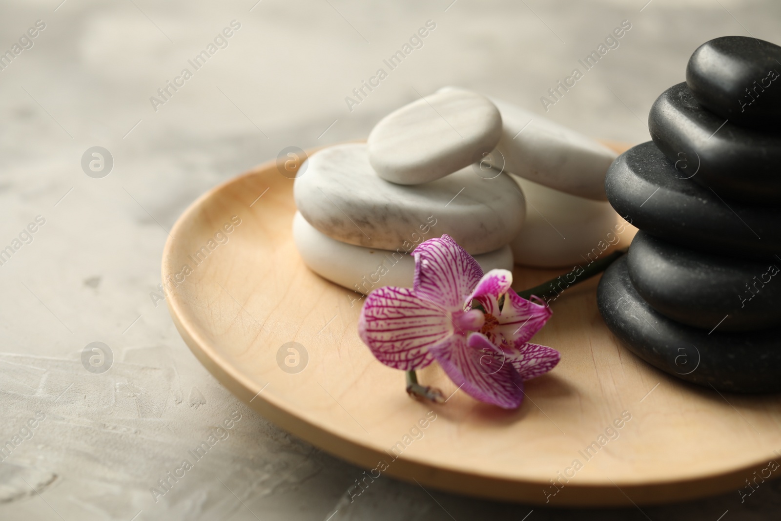 Photo of Spa stones and orchid flower on grey table, closeup