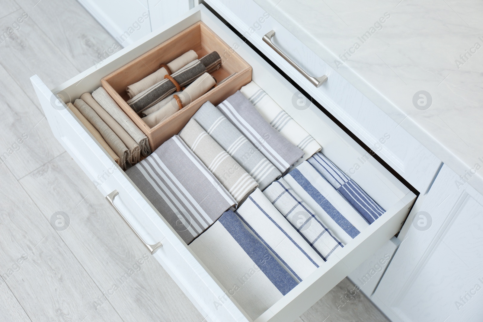Photo of Open drawer with folded napkins and towels indoors. Order in kitchen