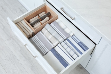 Open drawer with folded napkins and towels indoors. Order in kitchen