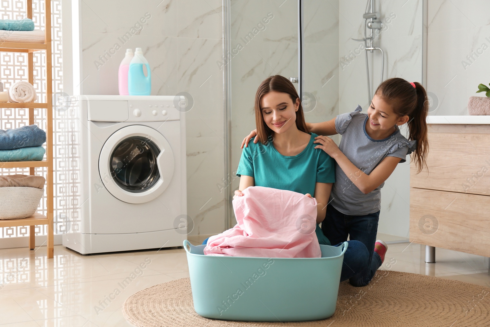 Photo of Mother and little daughter with clean laundry in bathroom