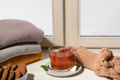 Photo of Woman with cup of tea at window, closeup. Winter drink