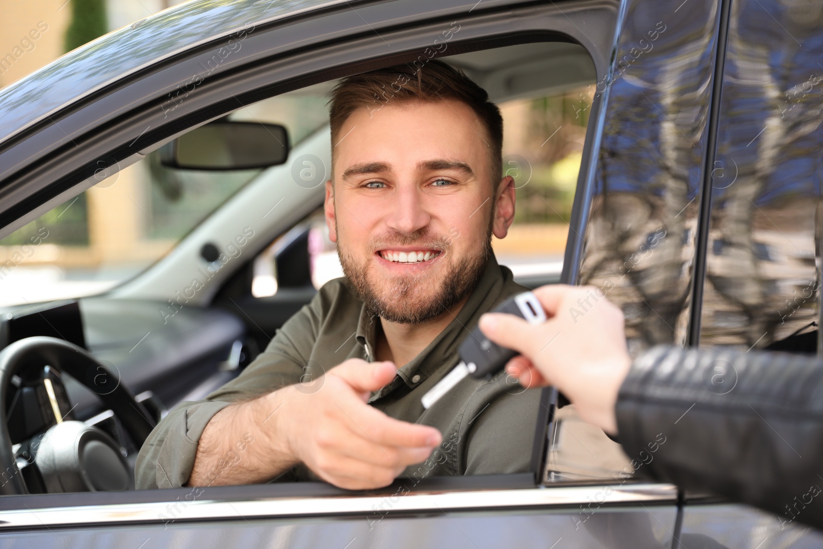 Photo of Salesperson giving car key to customer outdoors
