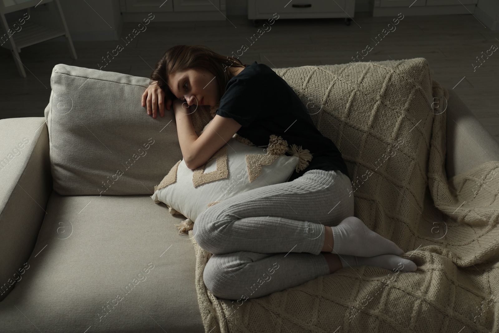 Photo of Sad young woman lying on sofa at home