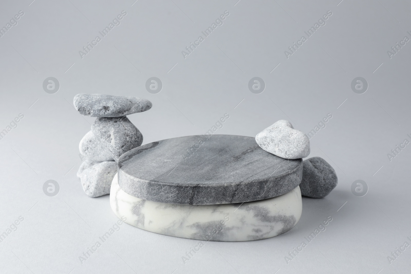 Photo of Presentation for product. Stone podium and pebbles on light grey background. Space for text