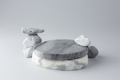 Photo of Presentation for product. Stone podium and pebbles on light grey background. Space for text