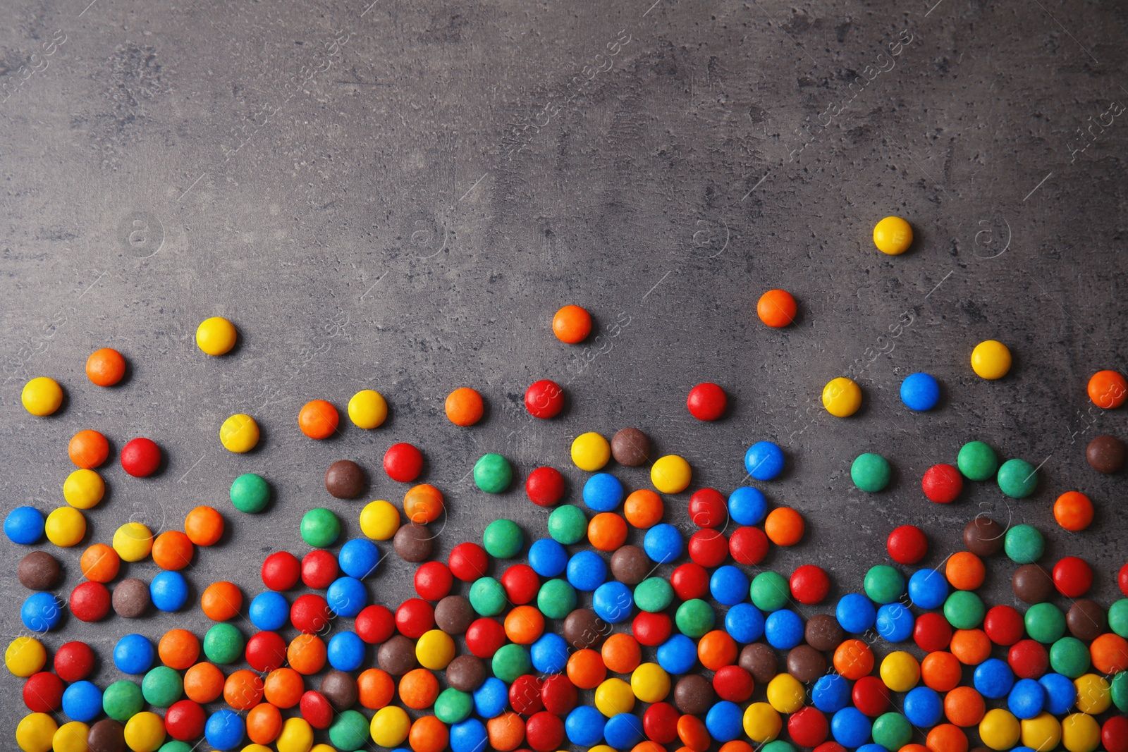 Photo of Colorful candies on grey background, top view. Space for text