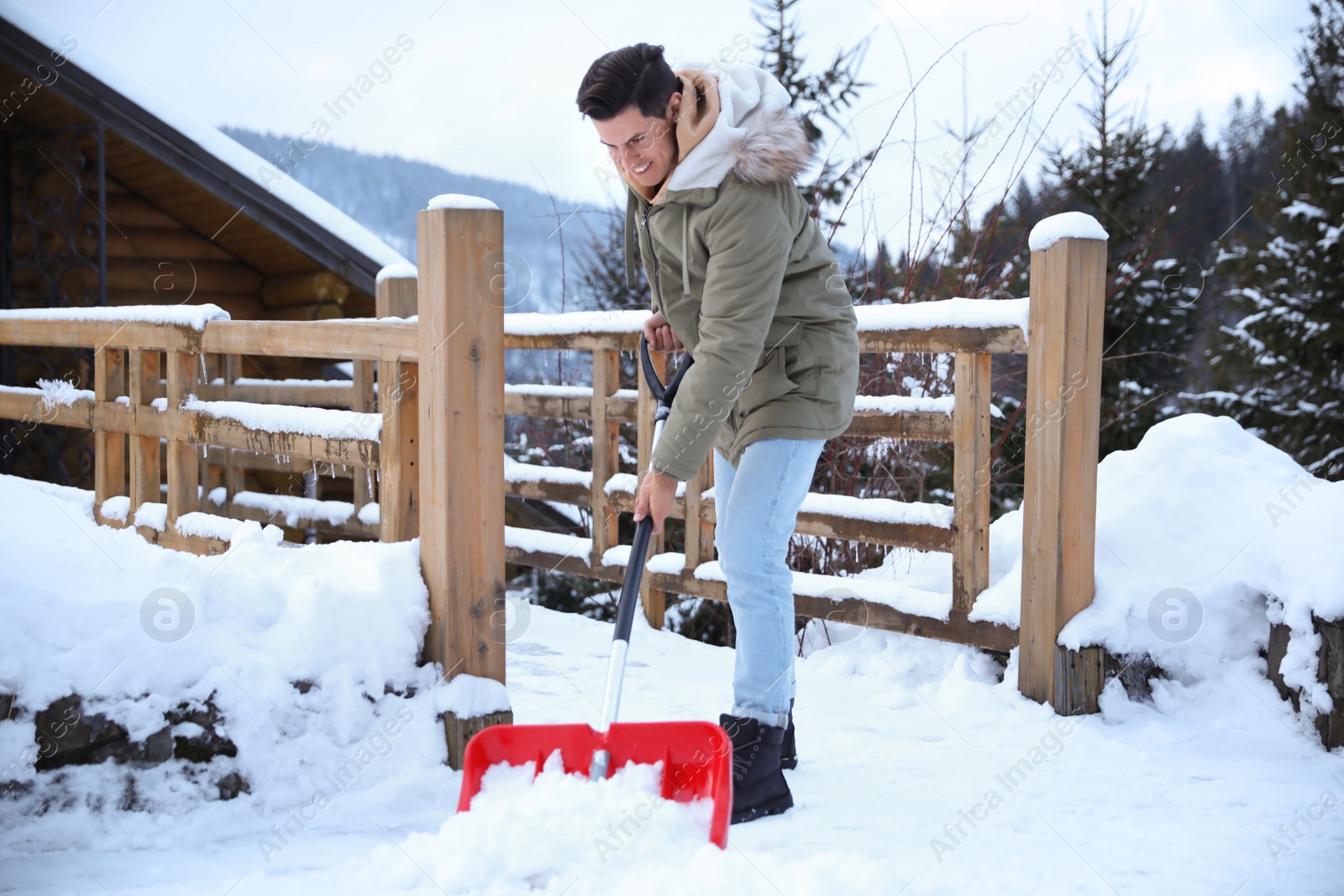 Photo of Man cleaning snow with shovel outdoors on winter day