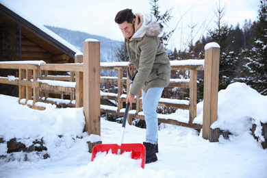 Man cleaning snow with shovel outdoors on winter day