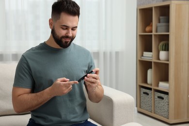 Photo of Diabetes test. Man checking blood sugar level with lancet pen at home. Space for text